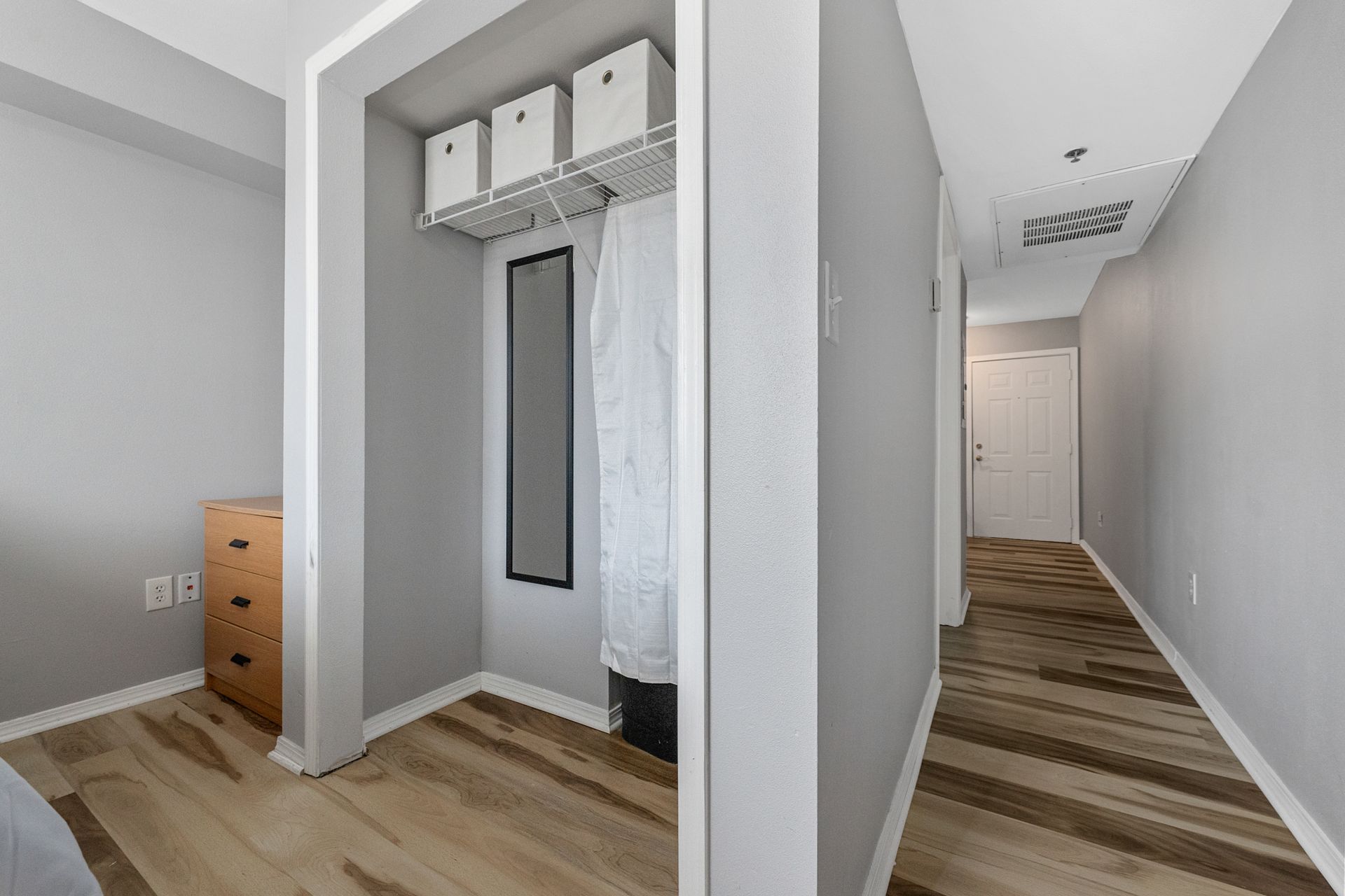 A bedroom with hardwood floors and a walk in closet.