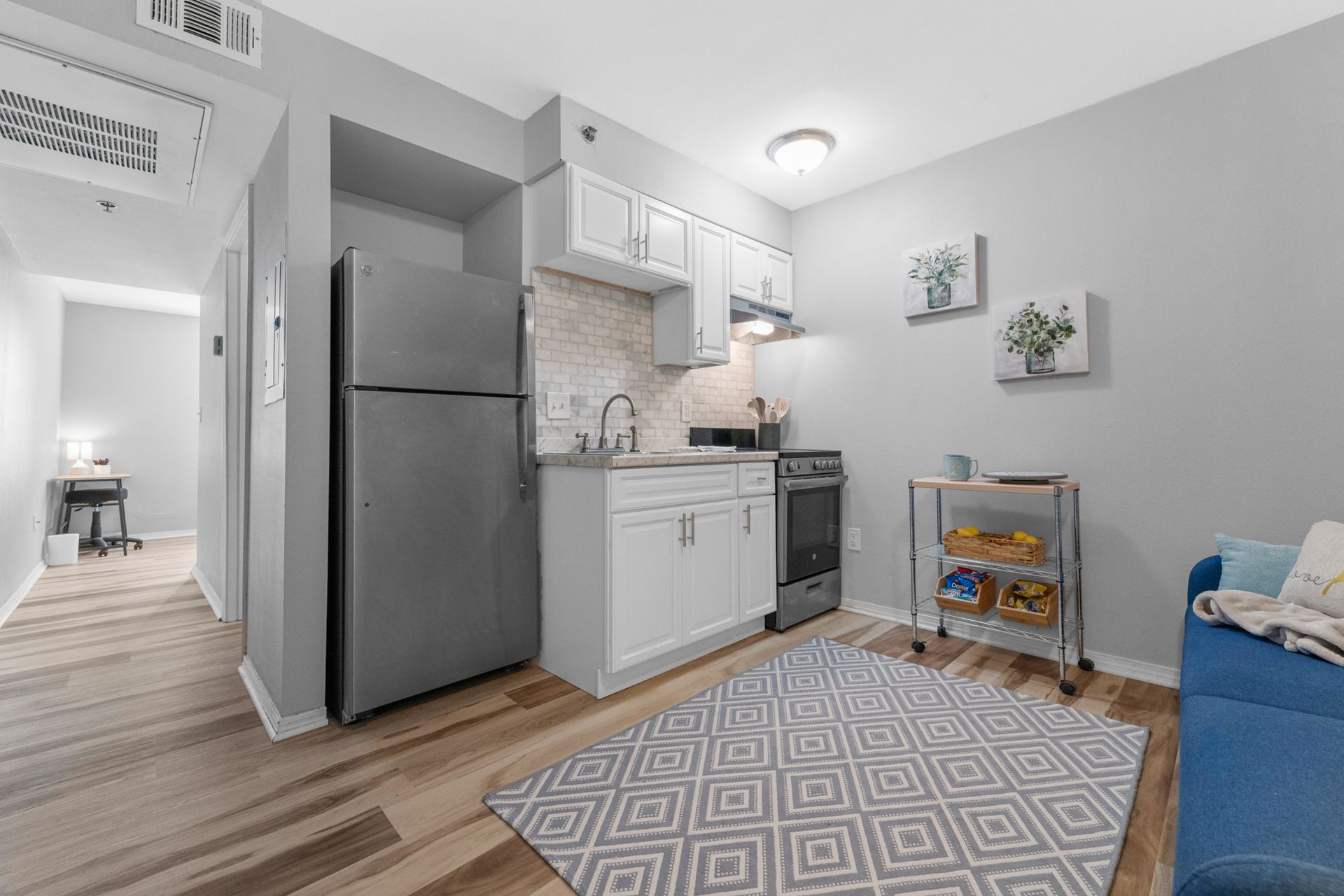 A living room with a couch , refrigerator , stove and sink.