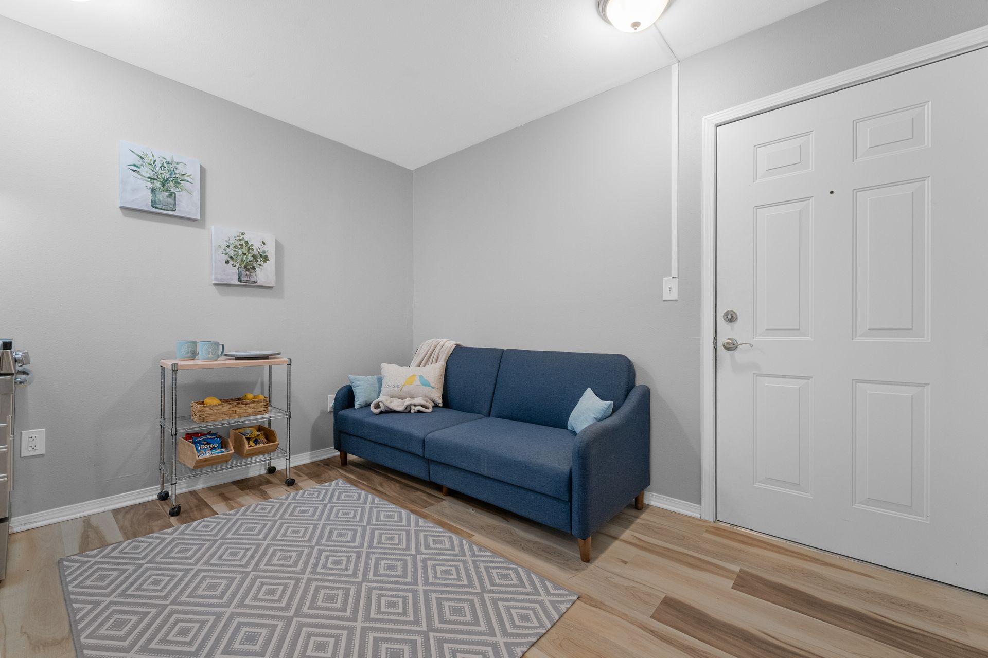 A living room with a blue couch and a rug.