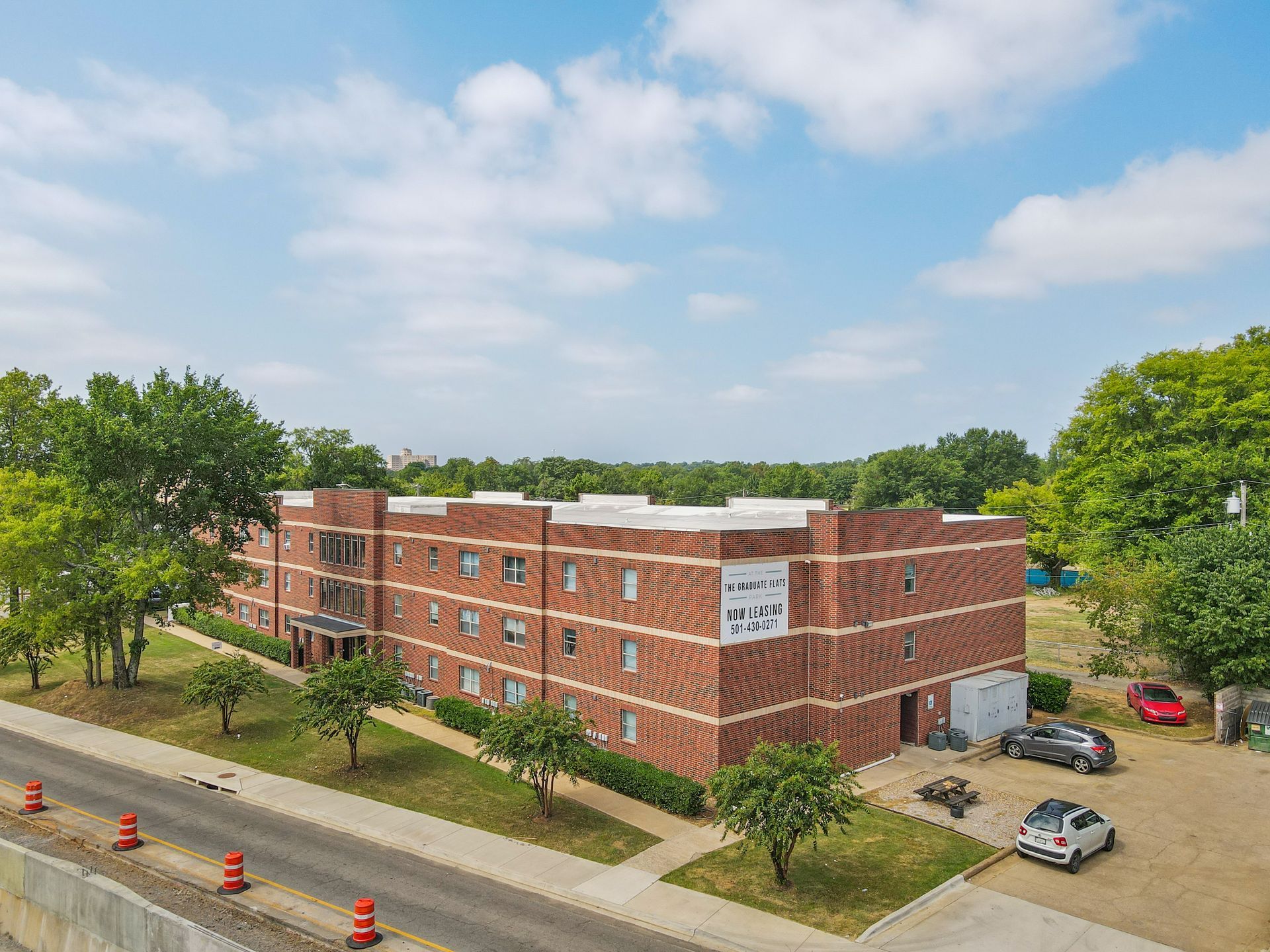 An aerial view of a large brick apartment building with cars parked in front of it.
