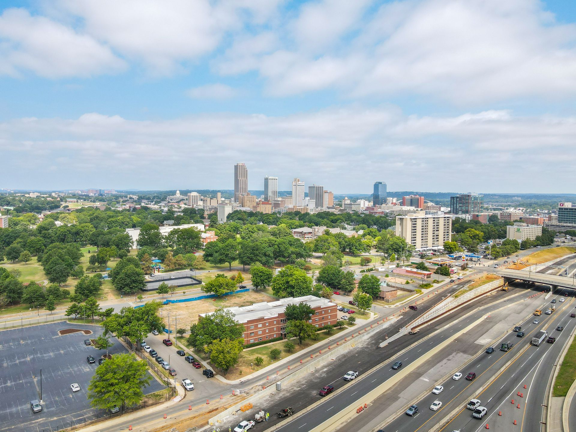 An aerial view of a city with a highway in the foreground and a park in the background.