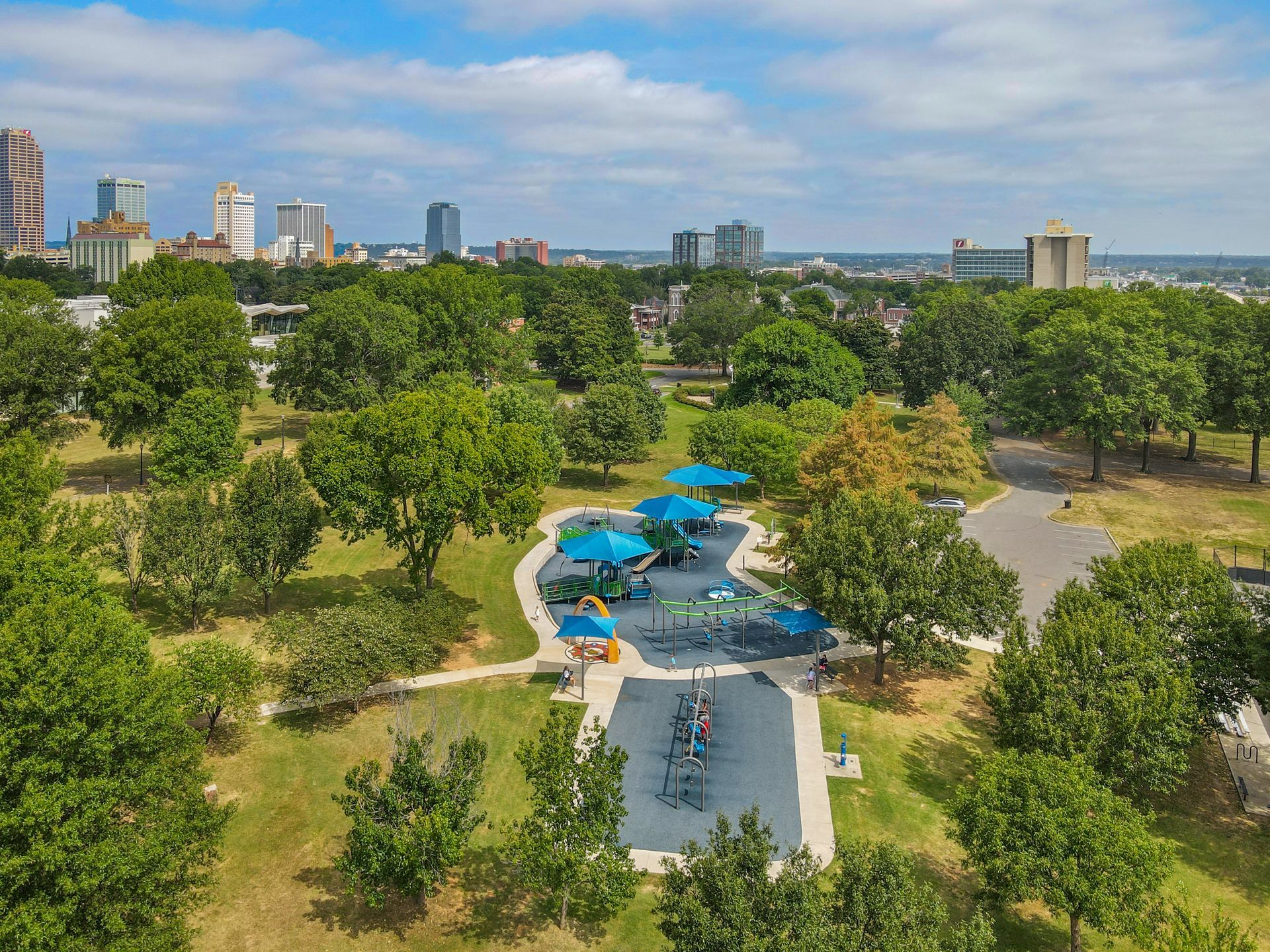 An aerial view of a park with a playground and a city in the background.