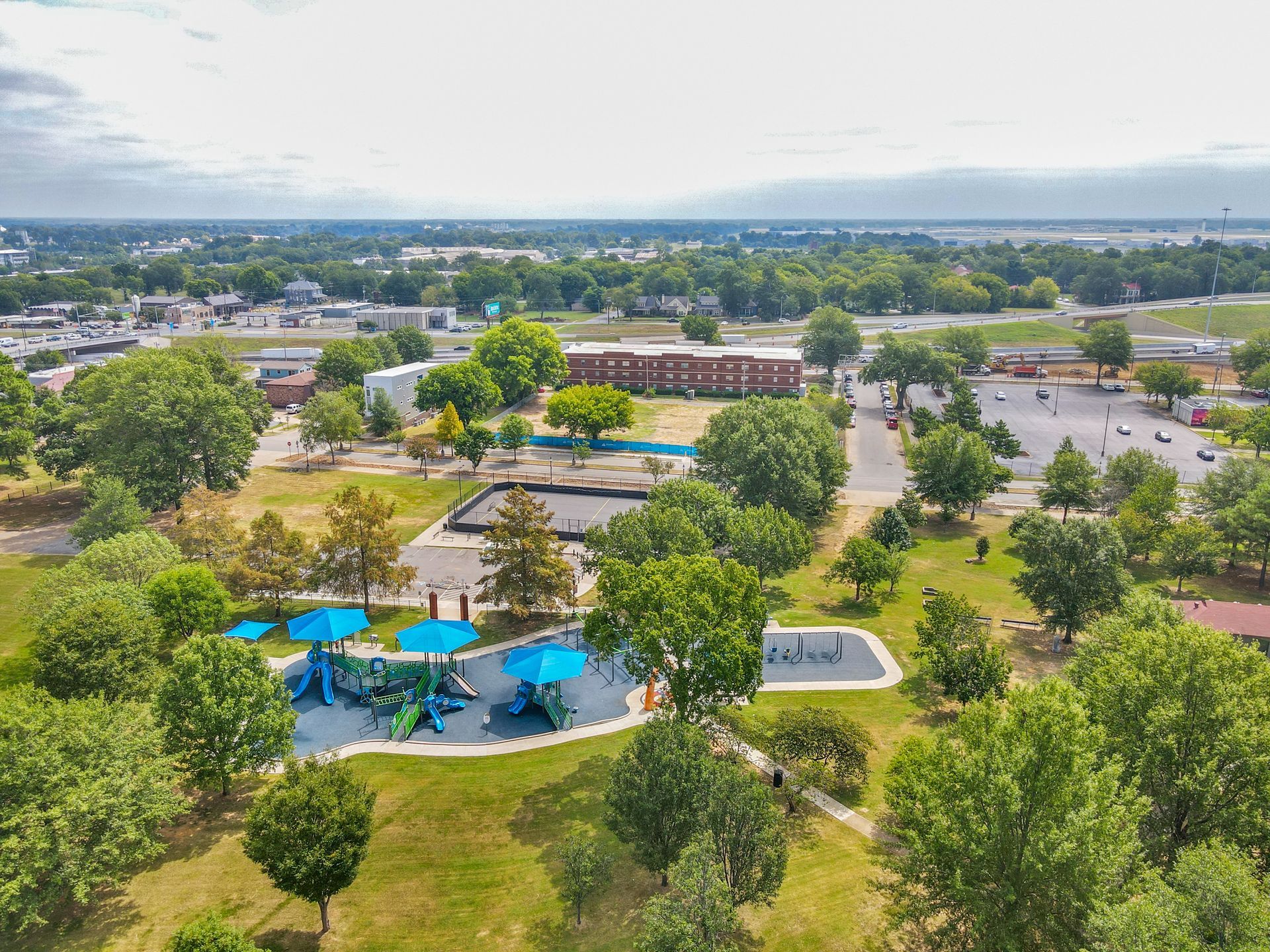 An aerial view of a park with a playground and umbrellas.