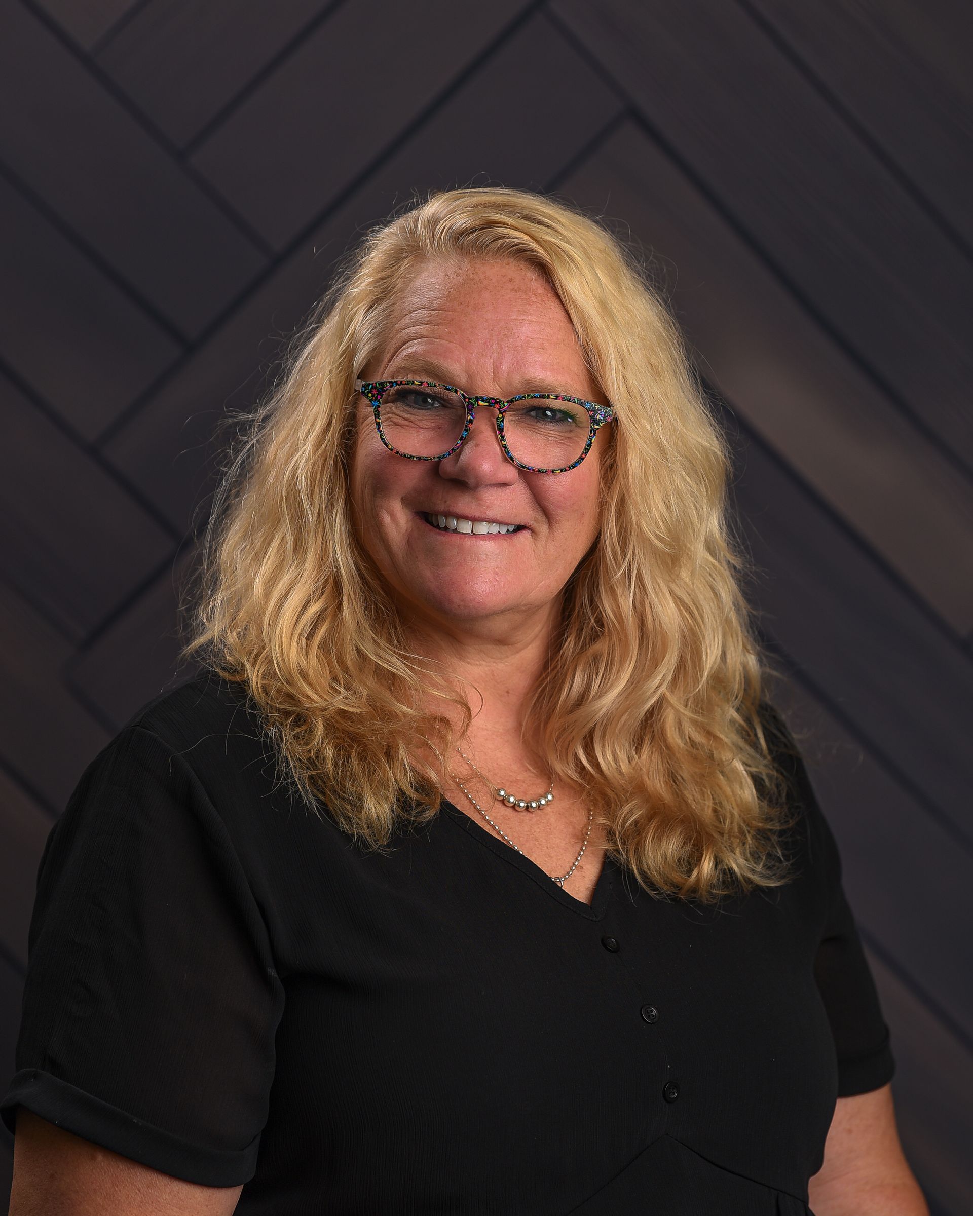 A woman wearing a plaid jacket and a black shirt is smiling for the camera.