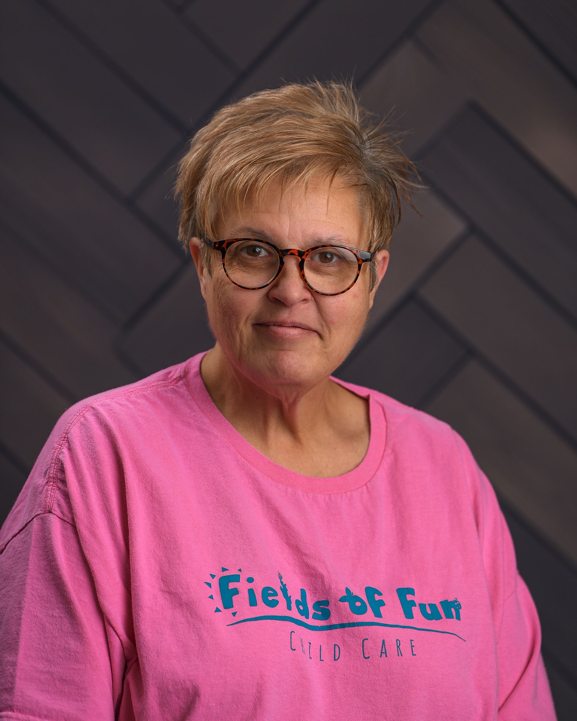 A woman wearing a plaid jacket and a black shirt is smiling for the camera.