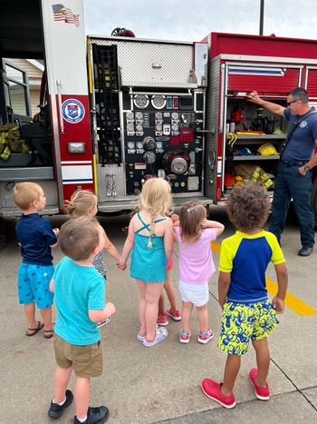A group of children are standing in front of a fire truck.