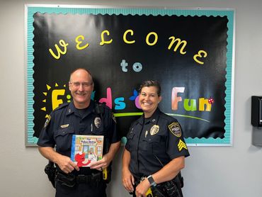 Two police officers are standing in front of a welcome sign