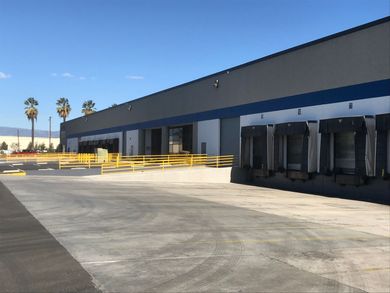 Empty loading dock with yellow railings and a blue industrial building under a clear sky