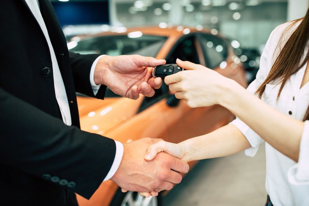 A Man Is Handing A Car Key To A Woman — Mackay Car & Commercial Pty Ltd In Paget, QLD