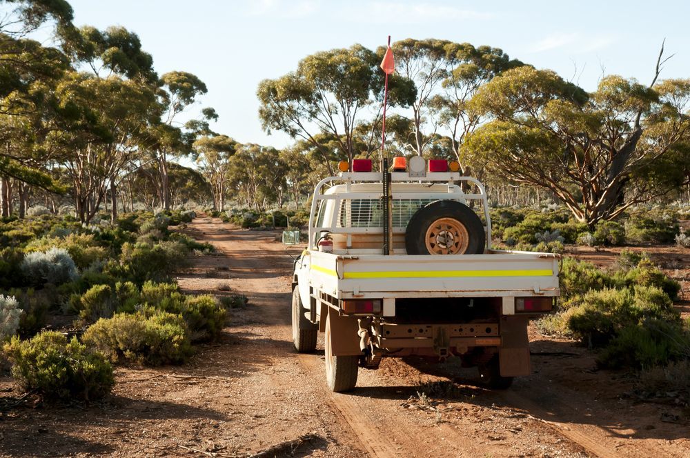 A Man Is Driving A Dump Truck On A Dirt Road — Mackay Car & Commercial Pty Ltd In Paget, QLD