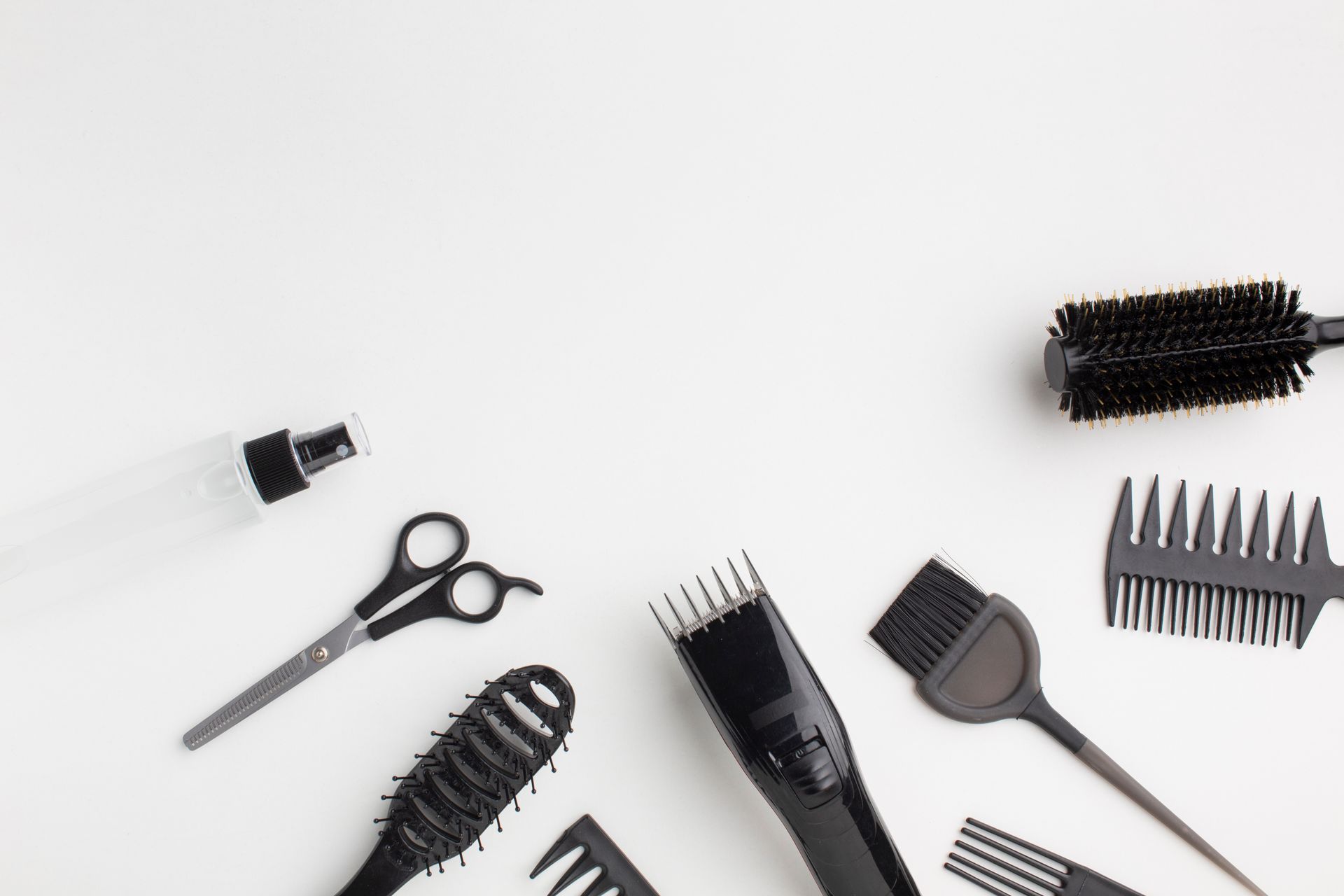 Diversas herramientas y cepillos para peinar el cabello esparcidos sobre un fondo blanco.