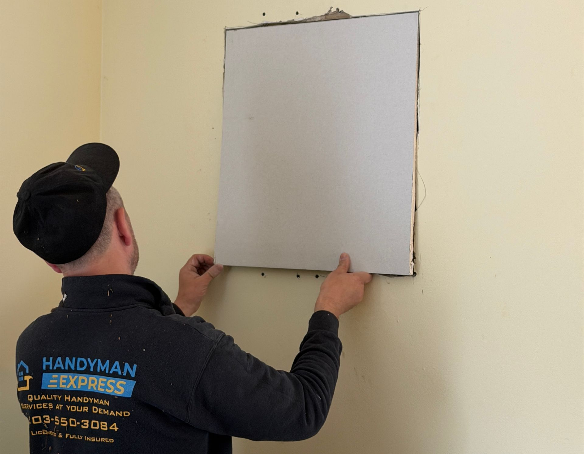 Worker installing a white wall panel in a beige room