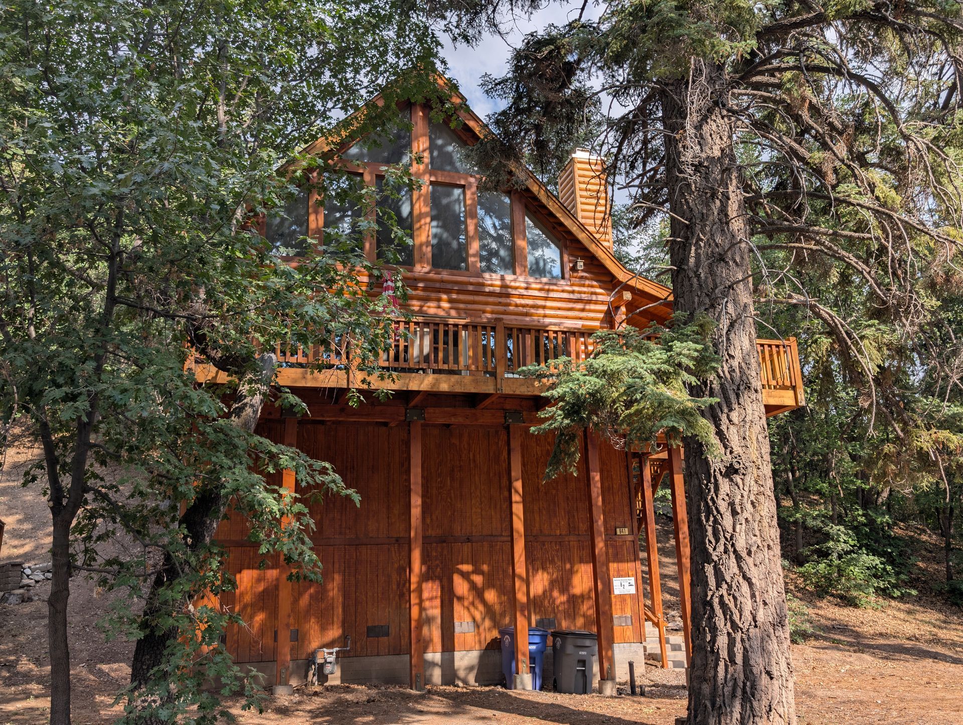 A large log cabin is surrounded by trees in the woods.