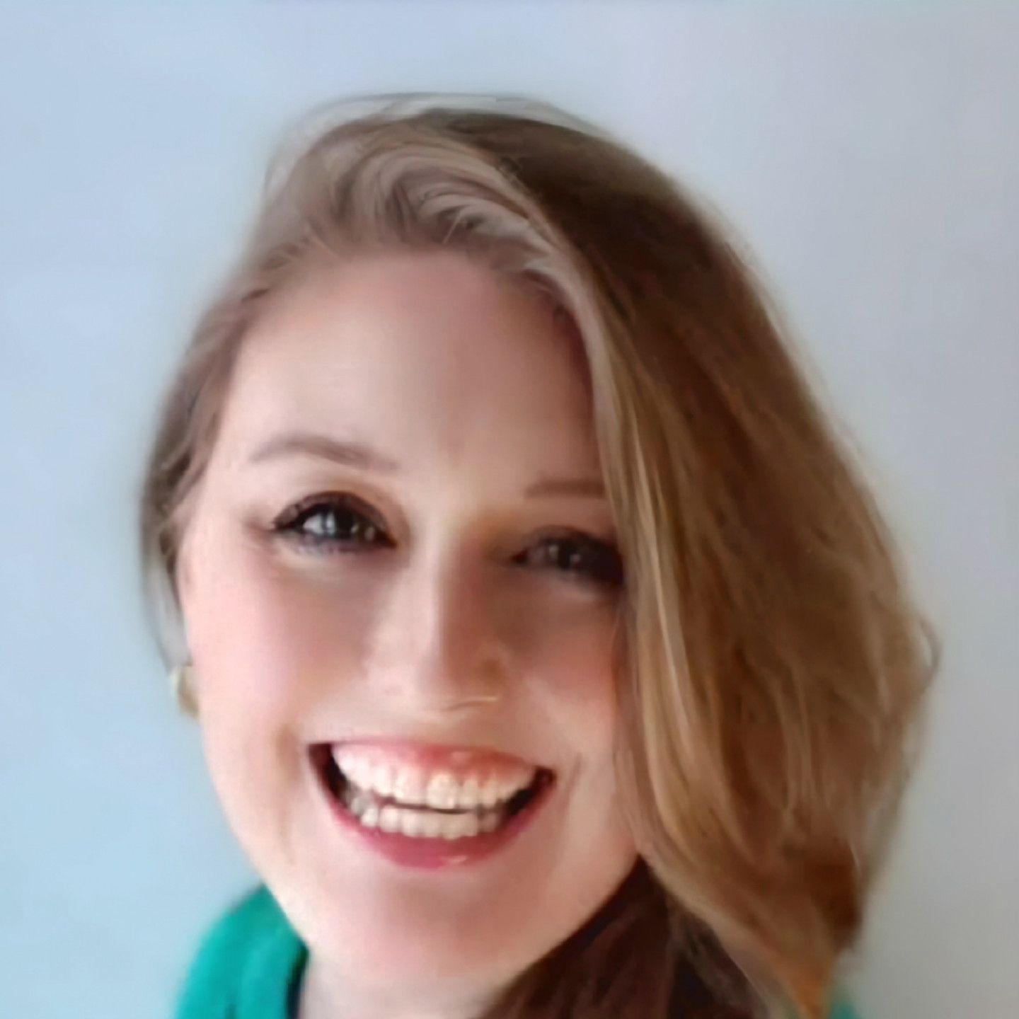 Smiling person with short blonde hair against a light blue background