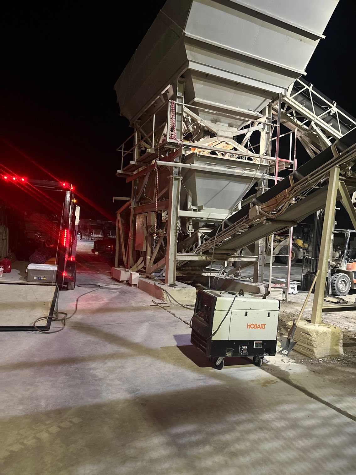 Industrial machinery lit at night with generator nearby