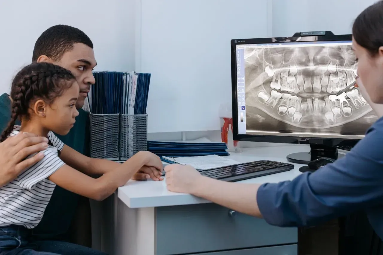 Dentist showing family a dental X-ray on a monitor in a clinic