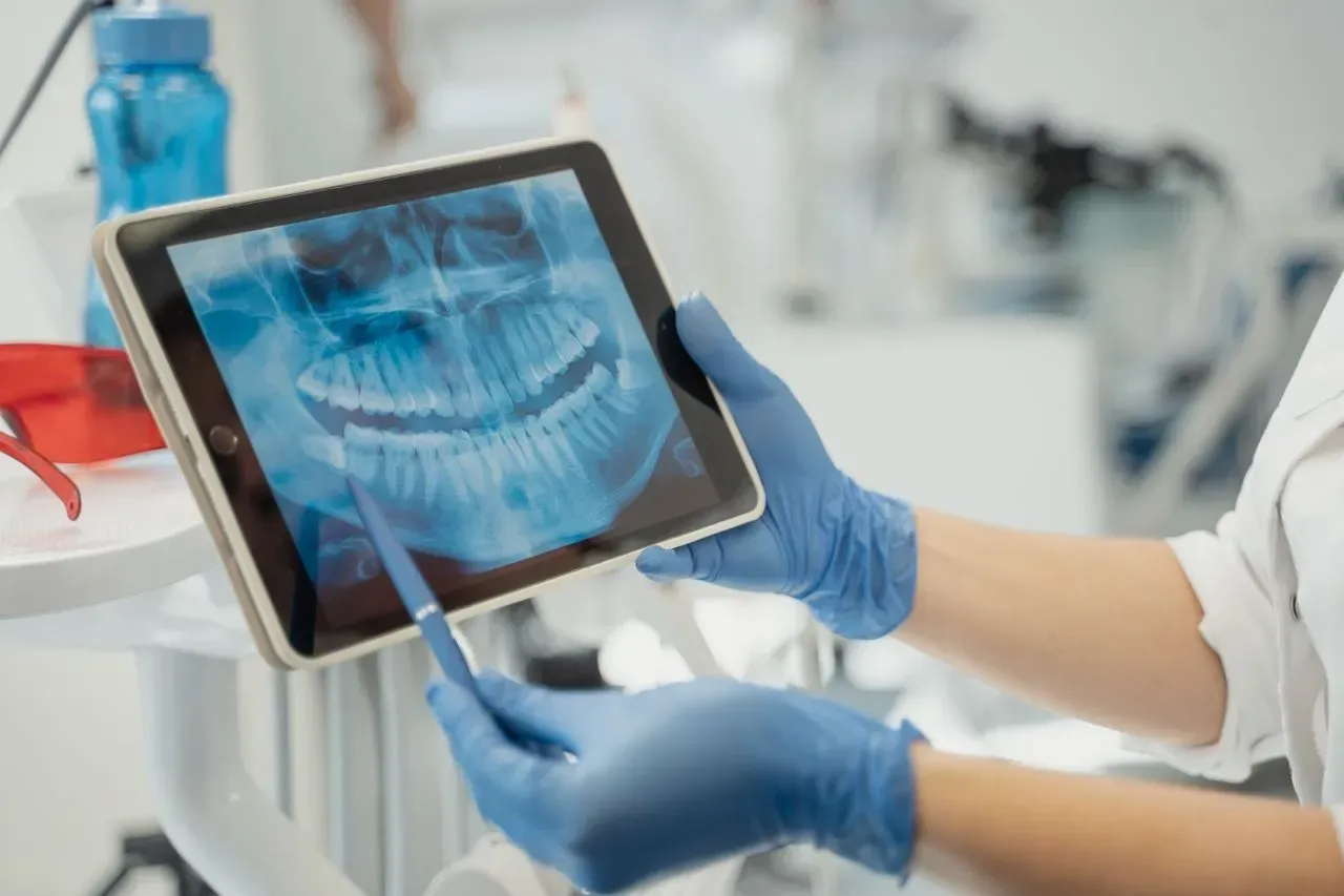 Dentist examining a dental X-ray on a tablet with a stylus in a clinic