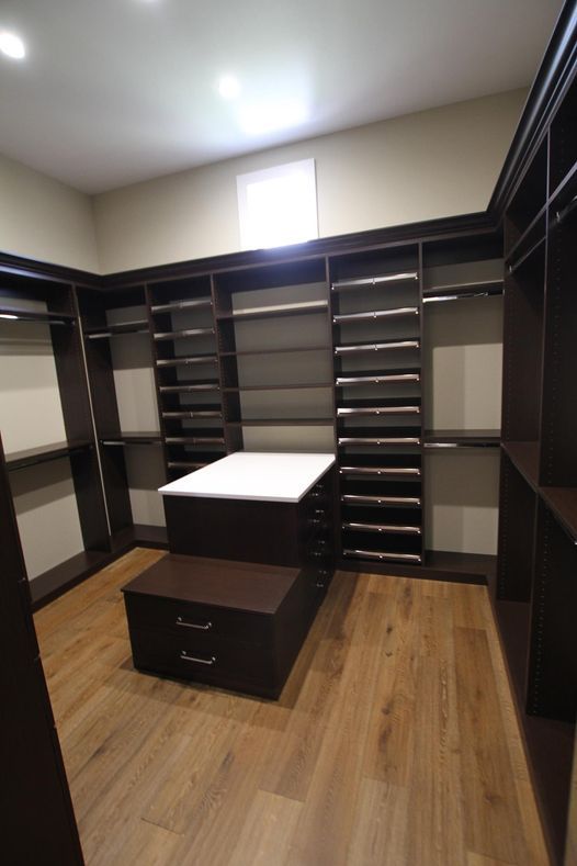 A walk in closet with lots of shelves and drawers