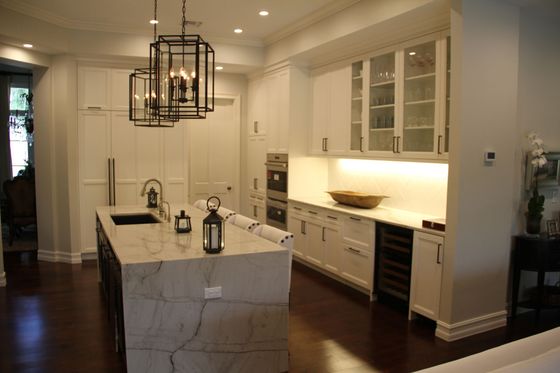 A kitchen with white cabinets and a large island in the middle