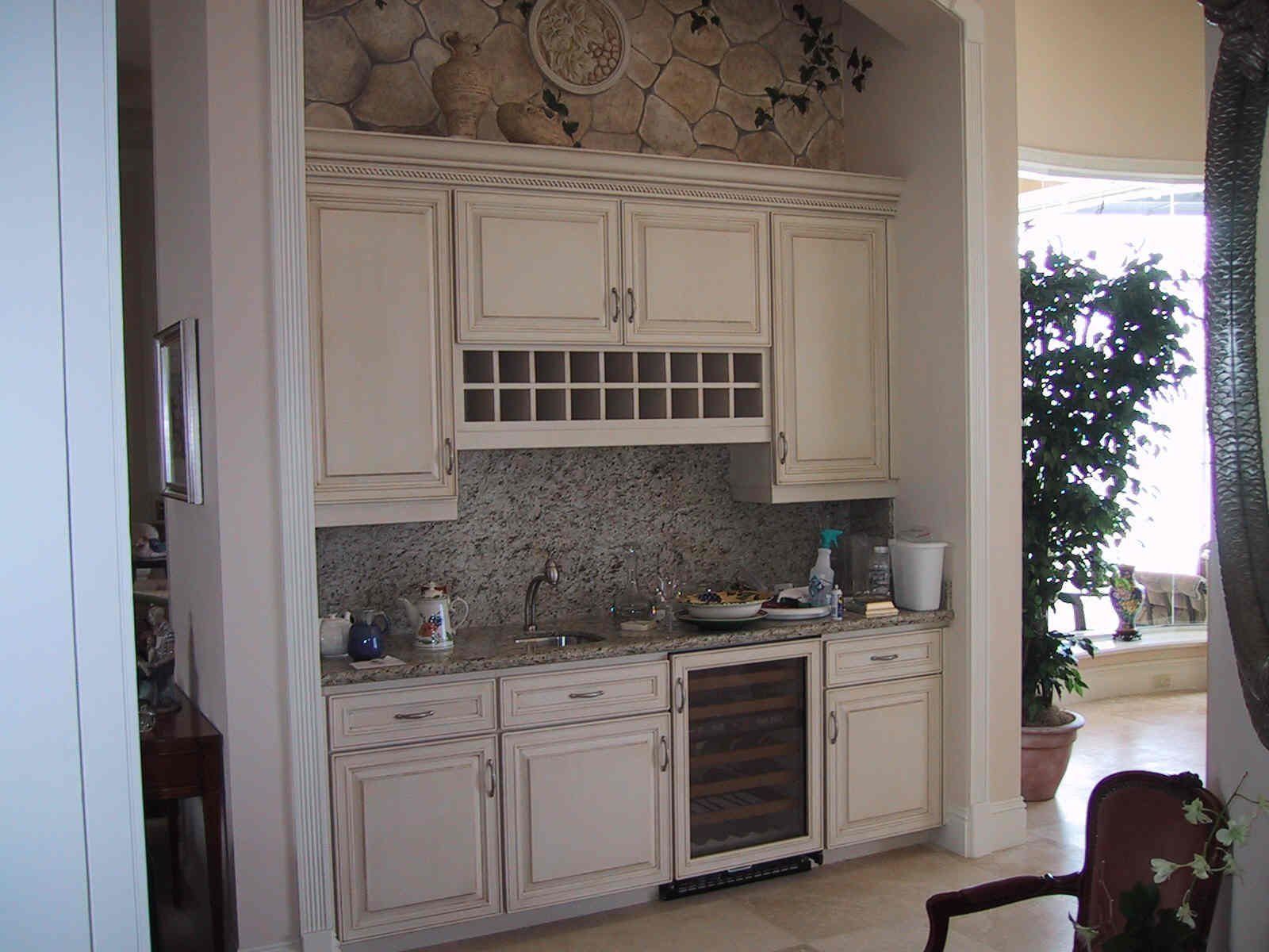 A kitchen with white cabinets and a wine cooler