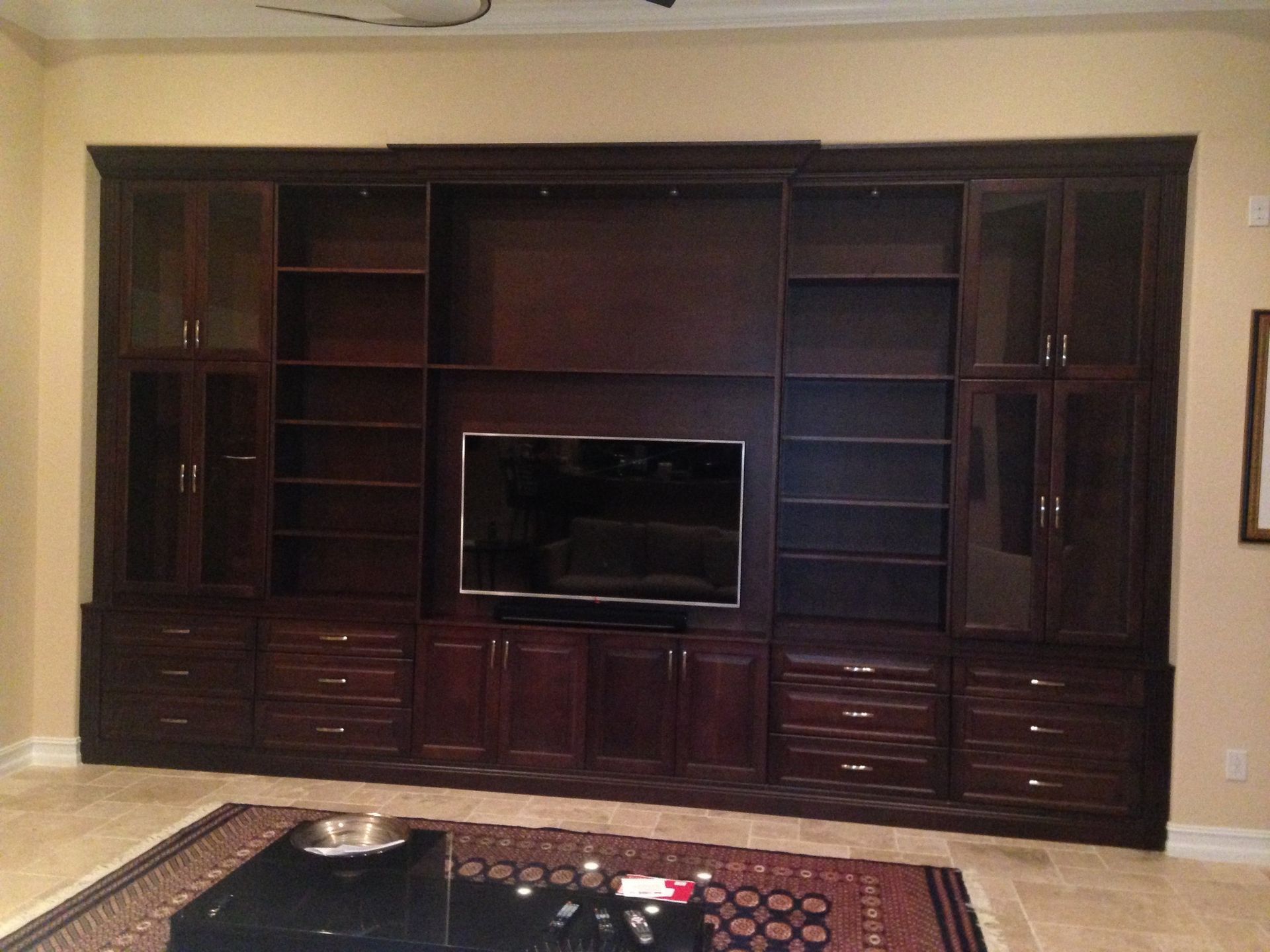 A living room with a large entertainment center and a flat screen tv