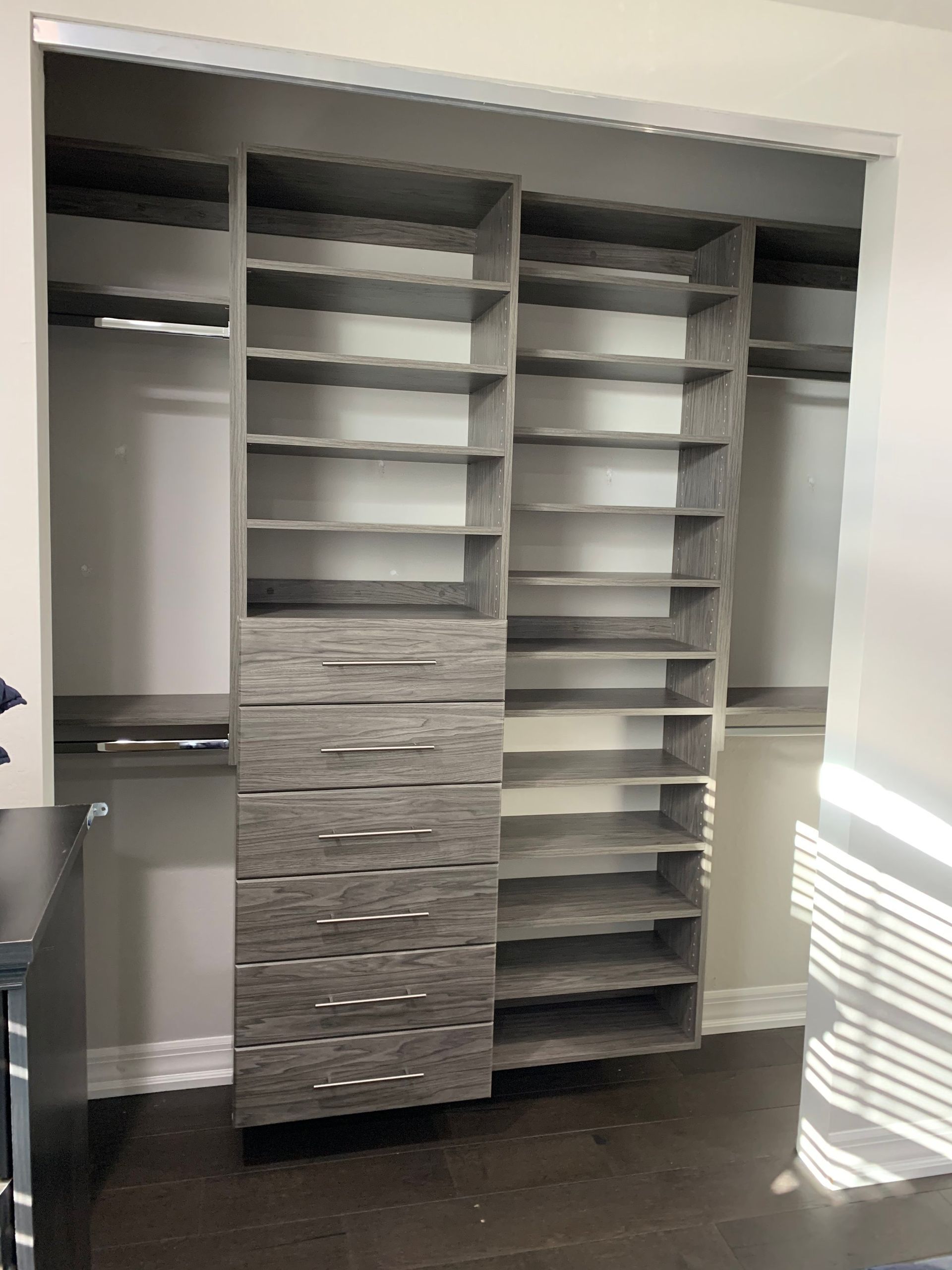 A walk in closet with lots of shelves and drawers.