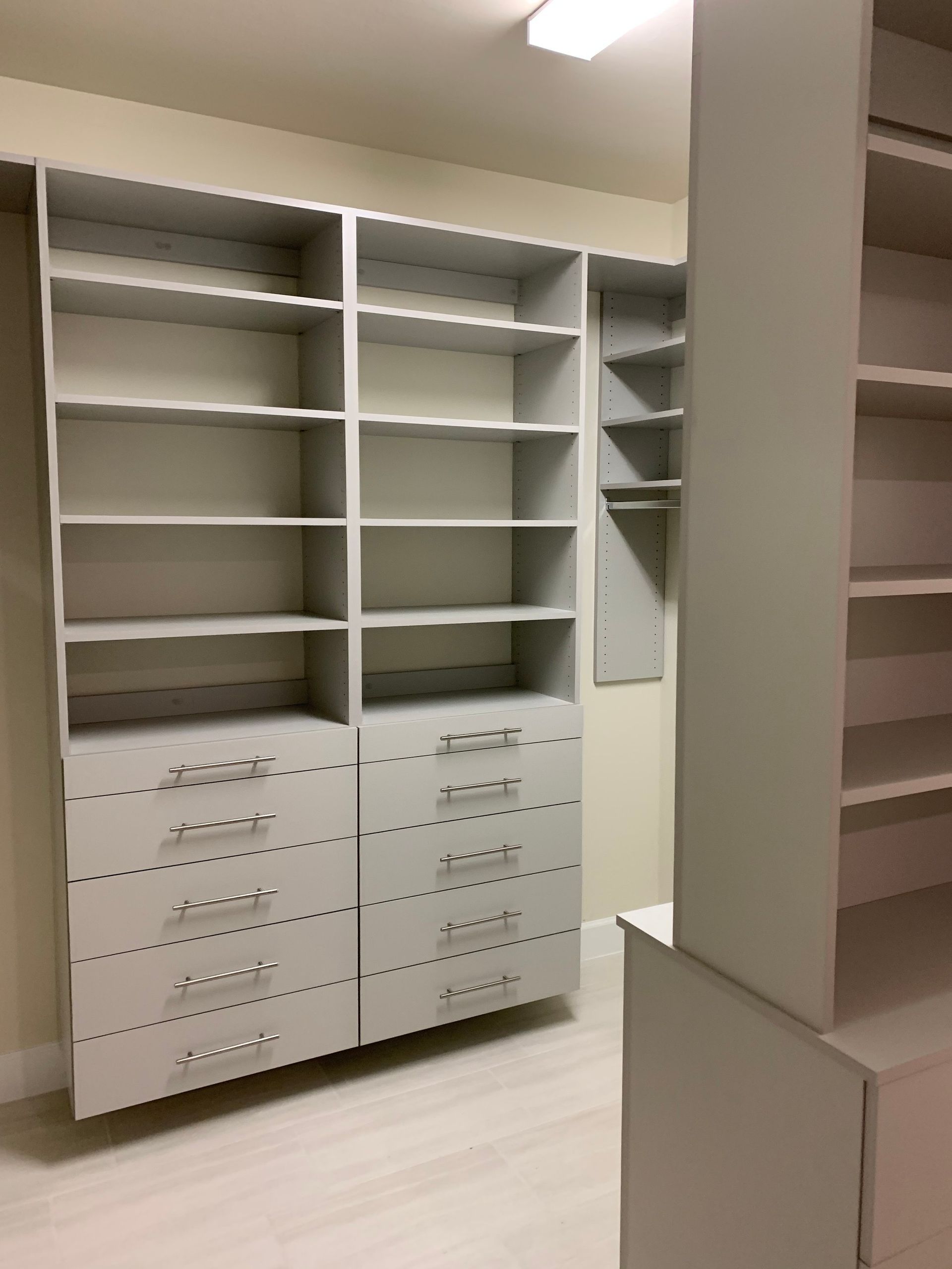 A walk in closet with lots of shelves and drawers
