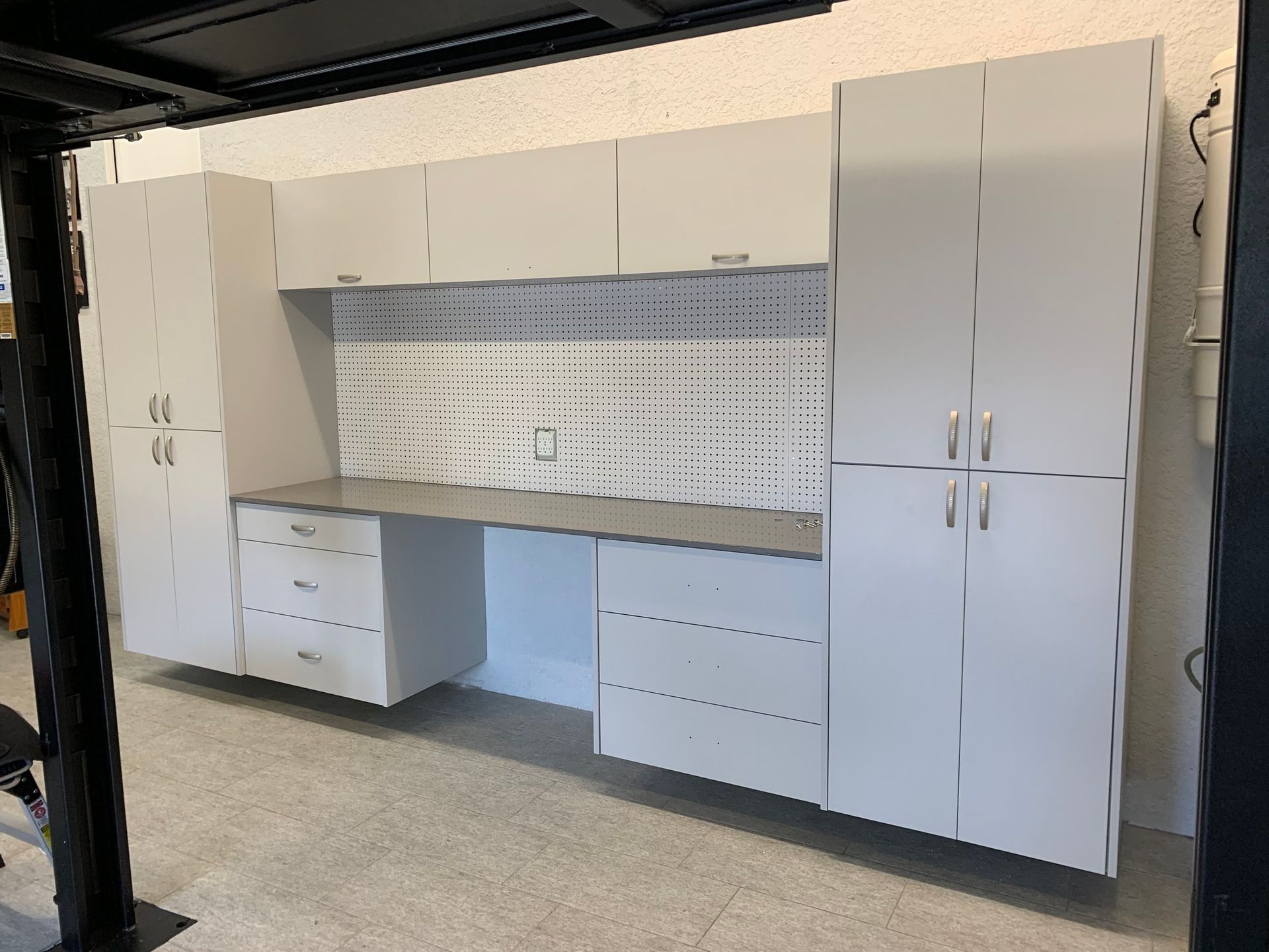 A garage with a lot of white cabinets and drawers.