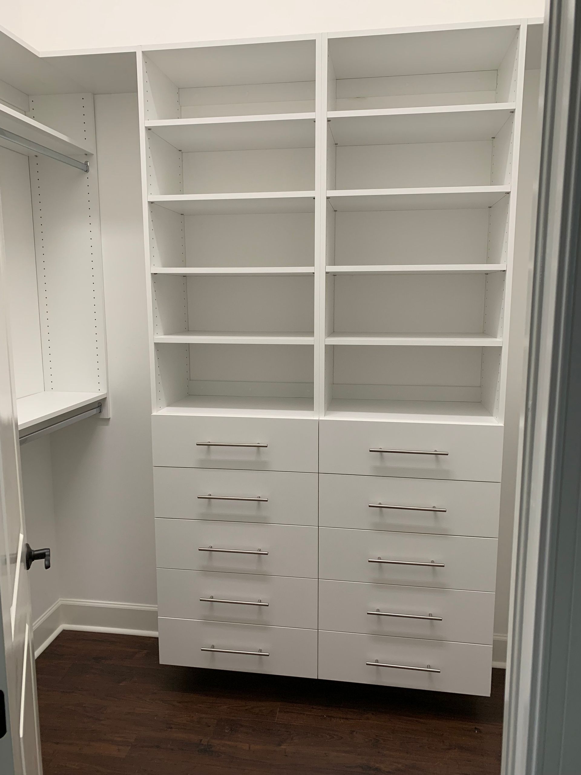 A walk in closet with lots of shelves and drawers.