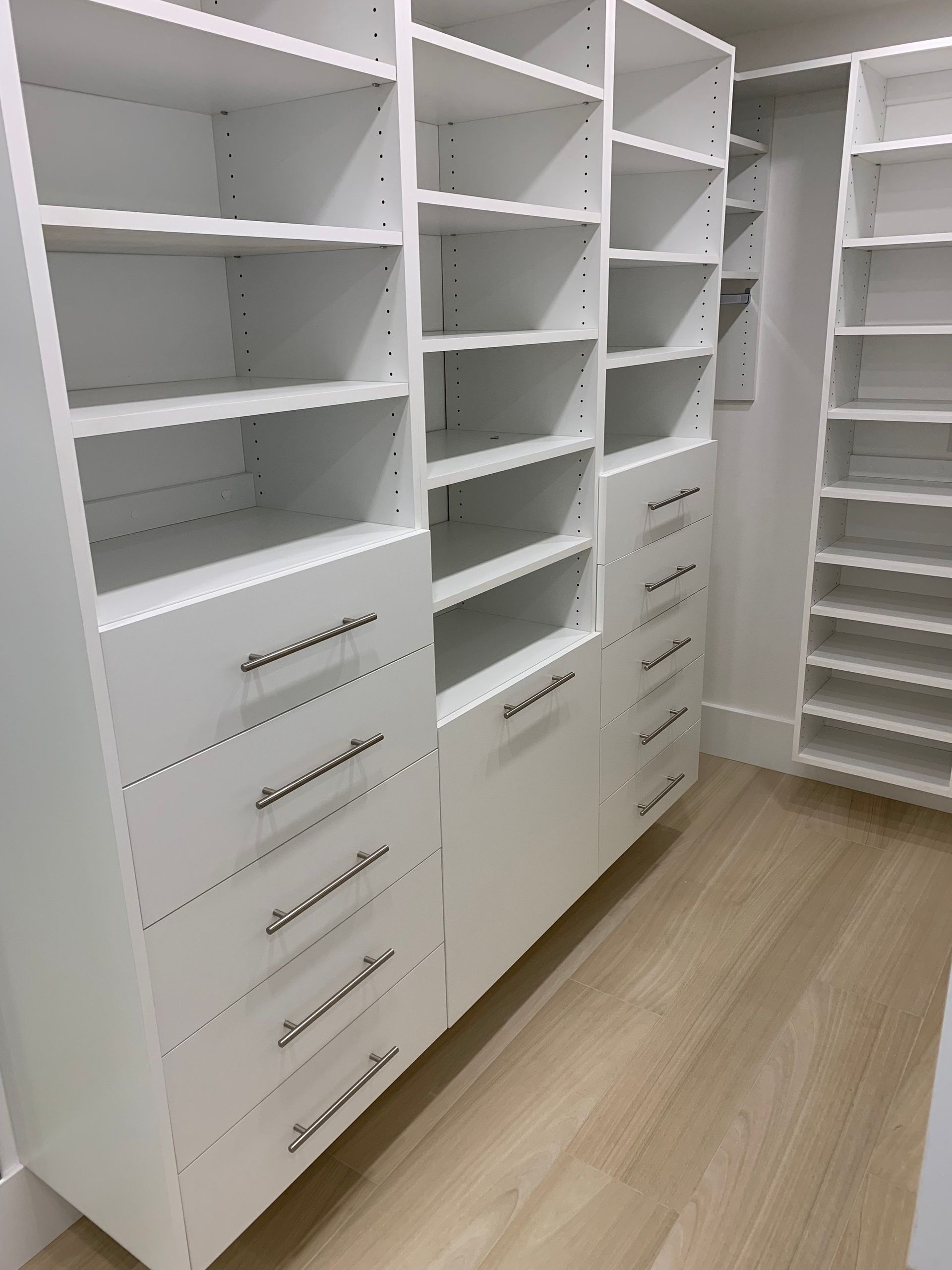 A walk in closet with lots of shelves and drawers.