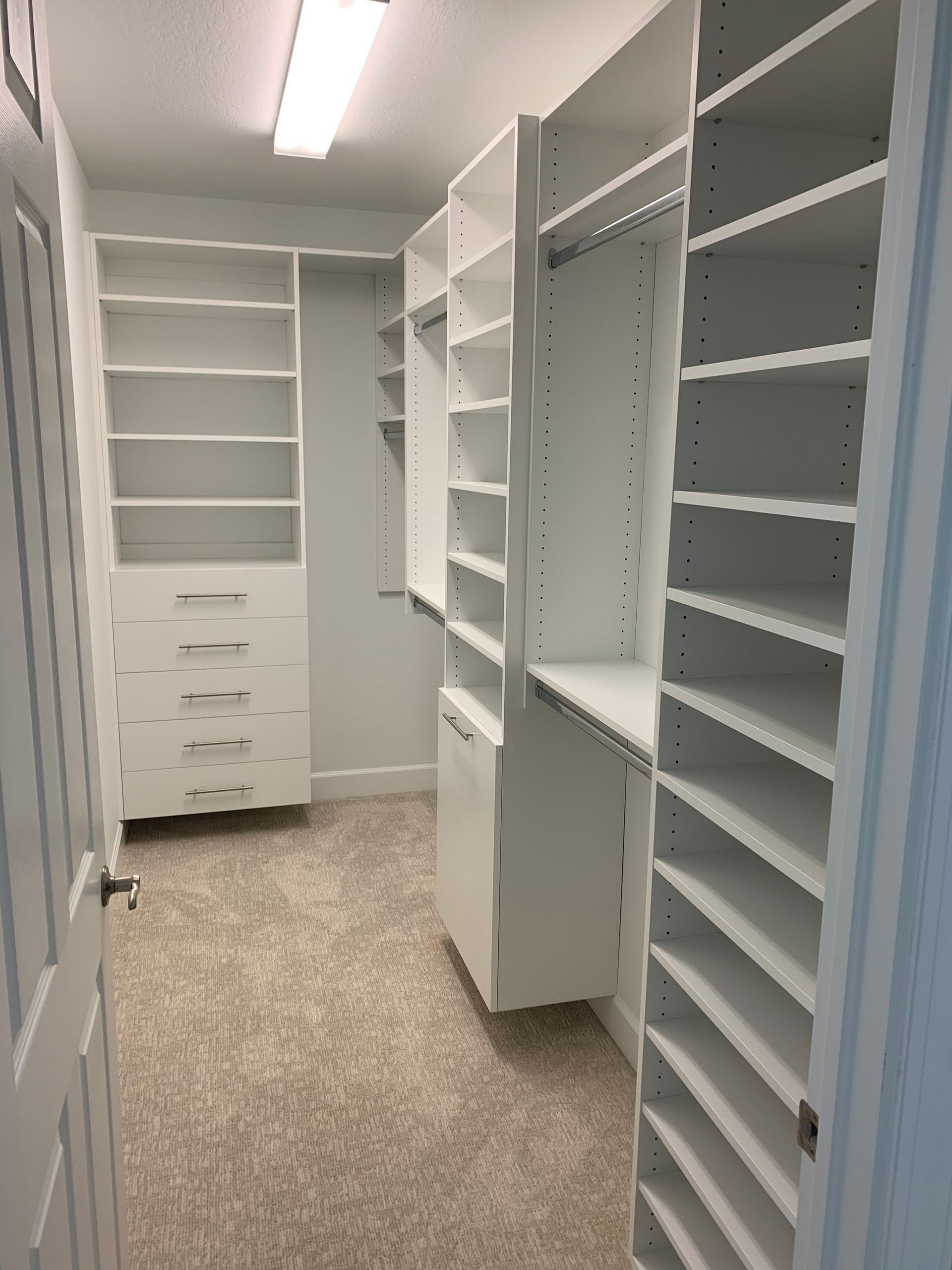 A walk in closet with lots of shelves and drawers.