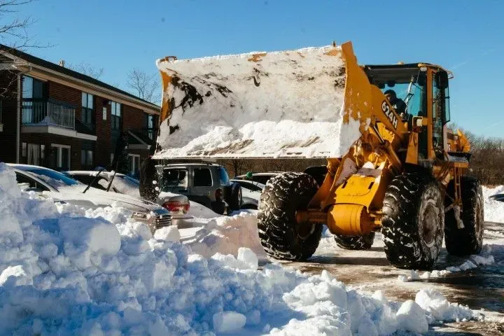 Large front-end loader relocating a massive pile of snow.