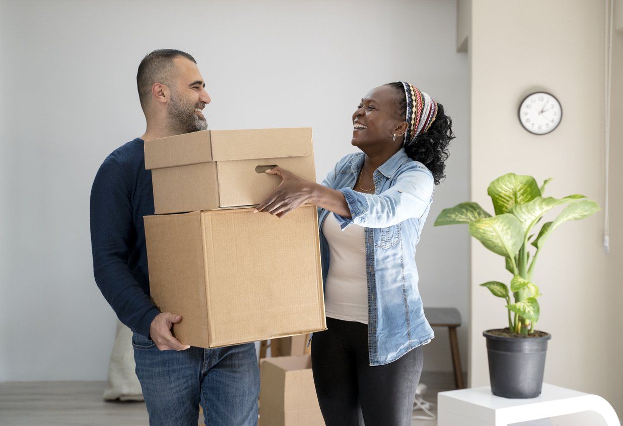 A couple packing things into cardboard boxes preparing for moving to the house.