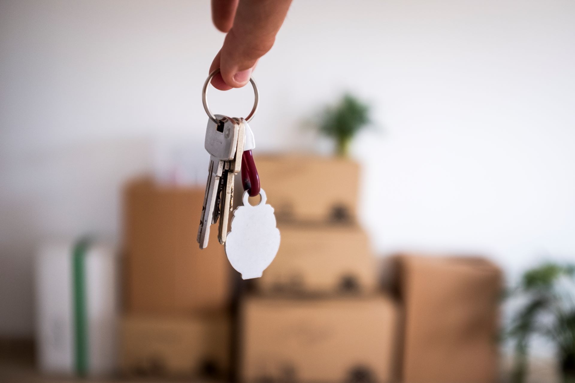 Close-up of the keys of the new empty apartment with moving boxes on the floor