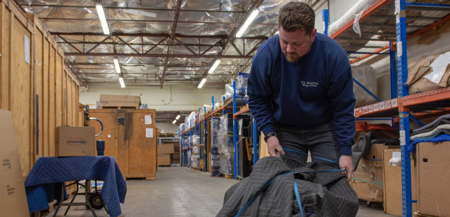 A man is carrying a large bag in a warehouse.