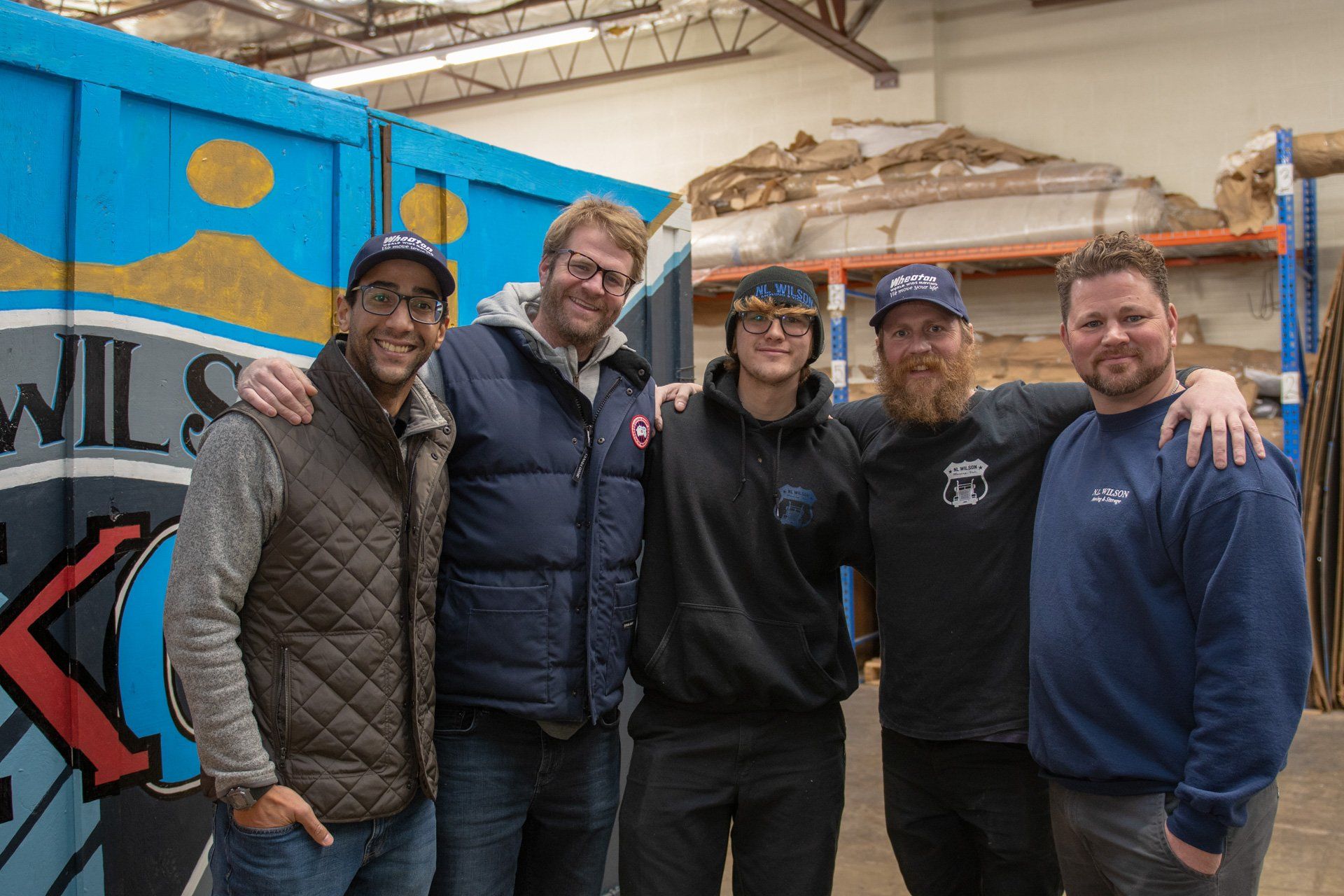 A group of men are posing for a picture in a warehouse.