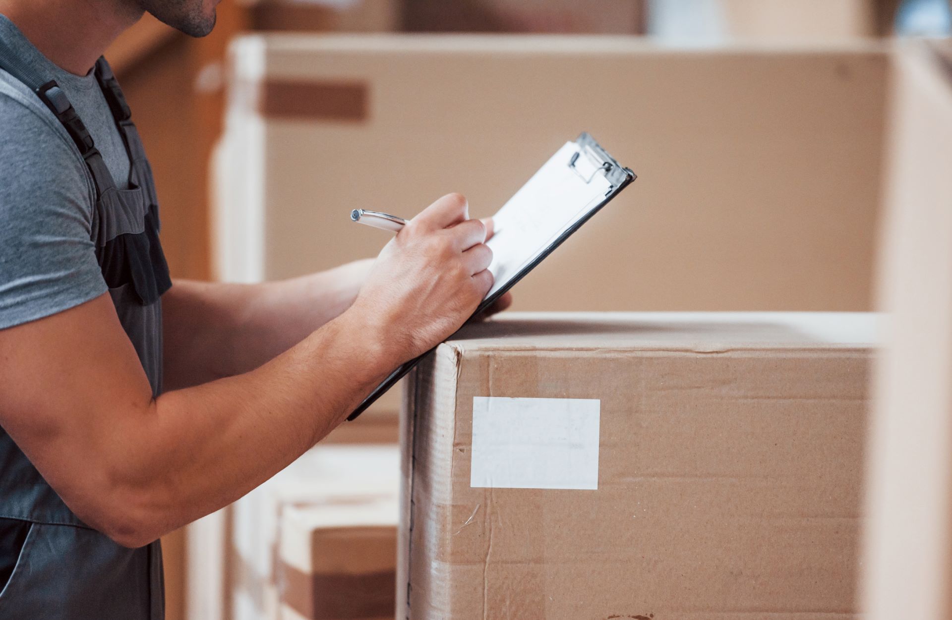Storage worker in uniform and notepad in hands checks production.