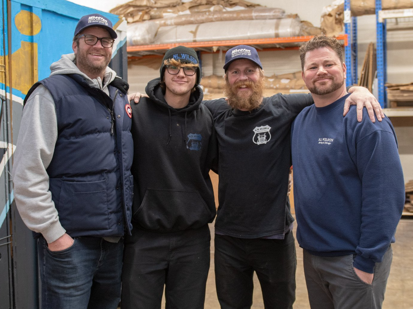 A group of men are posing for a picture in front of a warehouse.