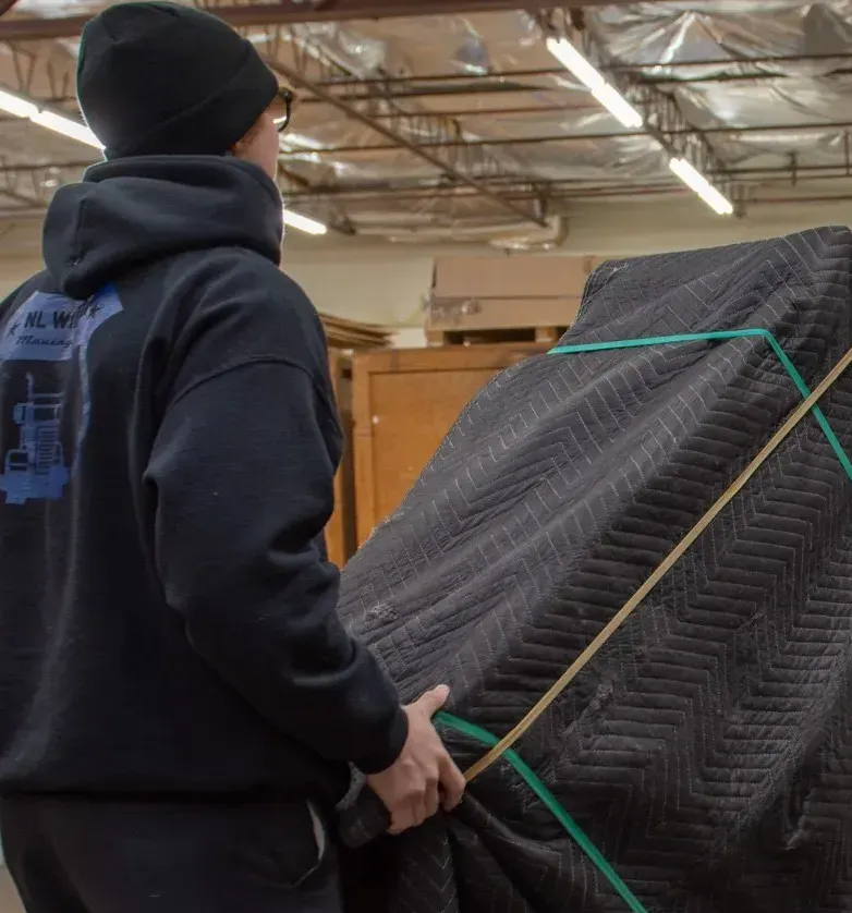 A man in a black hoodie is carrying a large piece of furniture