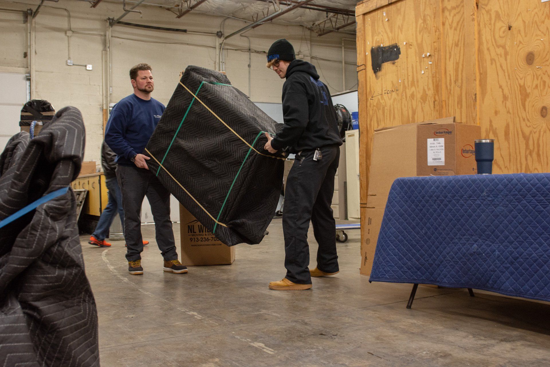 A group of men are moving a large piece of furniture in a warehouse.