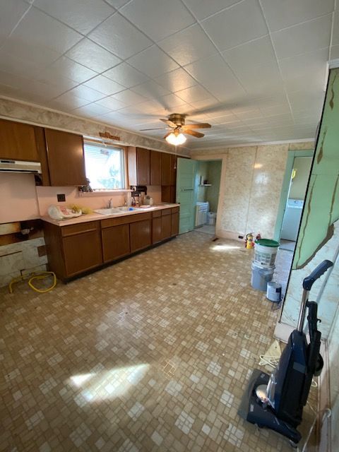 Kitchen with brown cabinets, patterned flooring, and a green wall section is under construction.