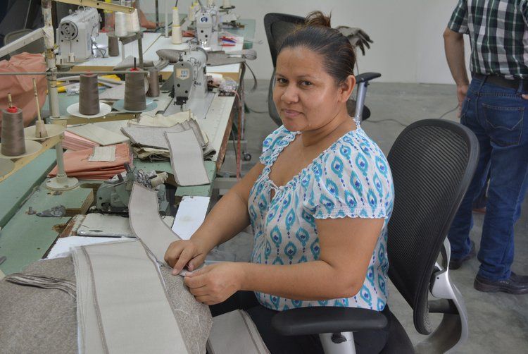A woman is sitting in a chair in front of a sewing machine.