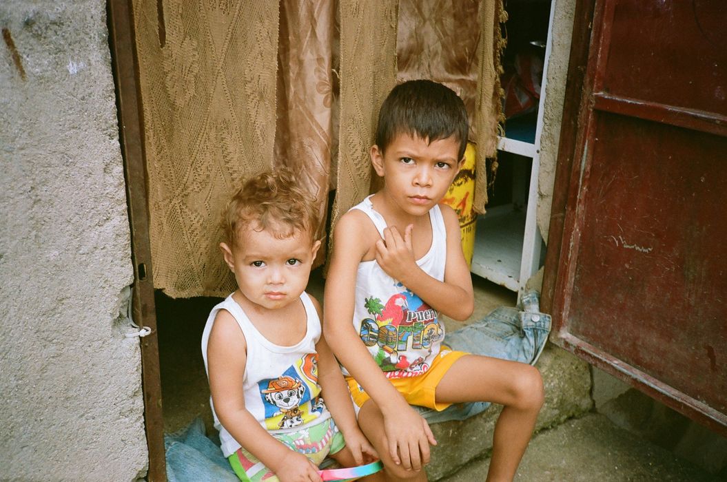 Two young boys are sitting next to each other in front of a door.