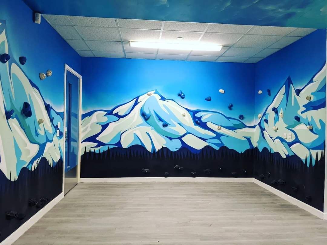 Blue room painted with snow-capped mountains and falling snow against a sky.