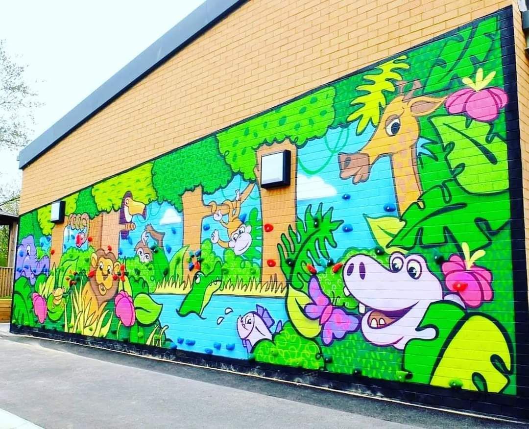 Jungle mural with giraffe, hippo, and other animals on a brick wall. Bright colors, cartoon style, outdoors.