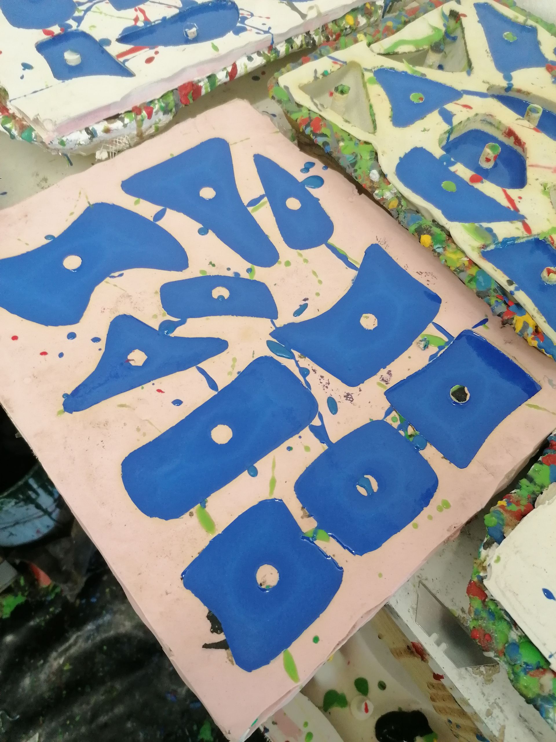 Blue shapes with white dots on pink background, spattered with paint.