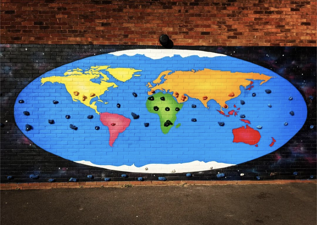 World map painted on a brick wall, blue with colorful continents and dark rock-like features.