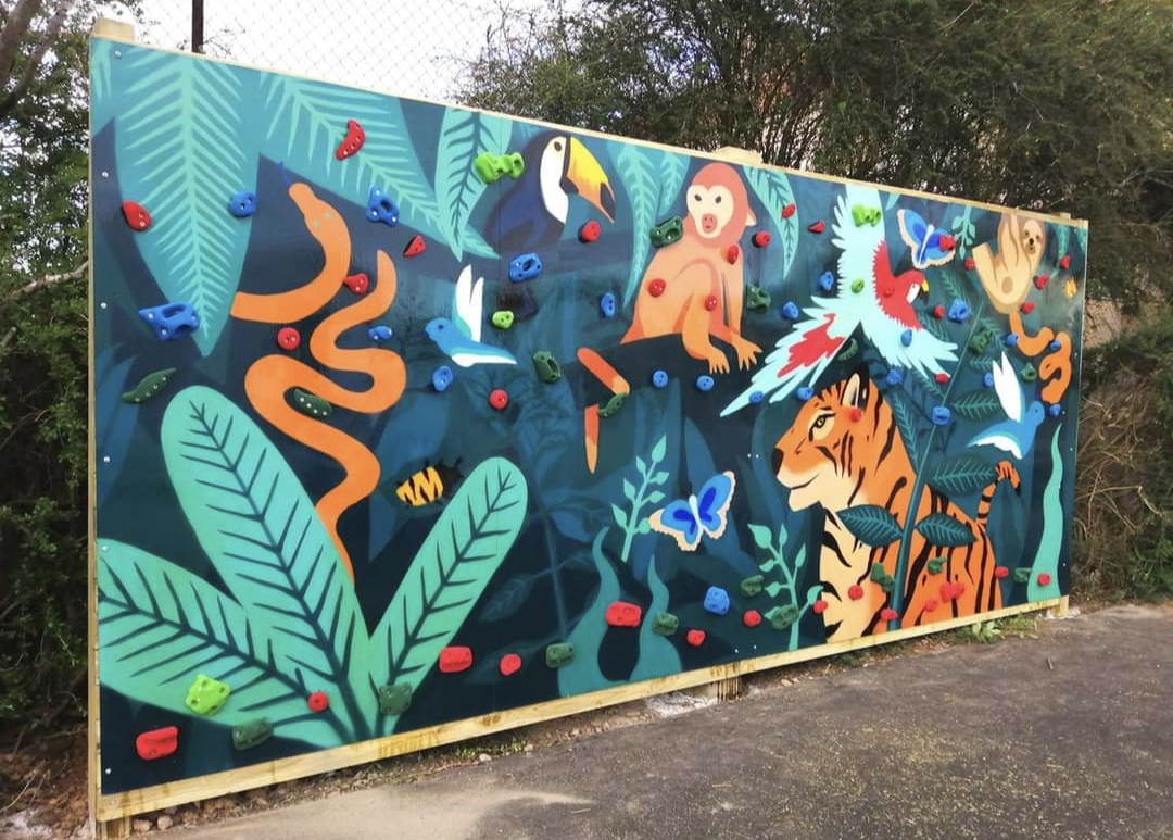 Jungle-themed climbing wall with colorful holds and painted animals.