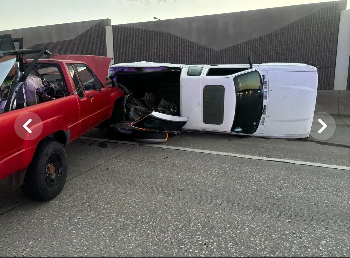 A red truck and a white SUV involved in a collision on a highway; SUV on its side.