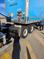 Blue Amazon semi-truck hooked to a trailer, fueling.  A person stands nearby.